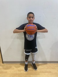 a young boy holding a basketball in front of a wall