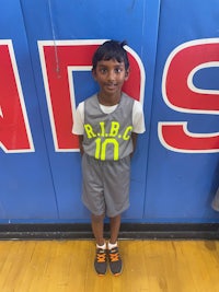 a young boy standing in front of a basketball court