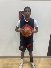 a young boy holding a basketball in front of a wall
