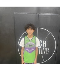 a young boy standing in front of a basketball court