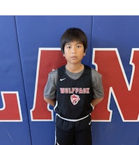 a young boy in a basketball uniform standing in front of a wall