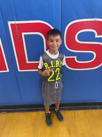 a young boy standing in front of a basketball court