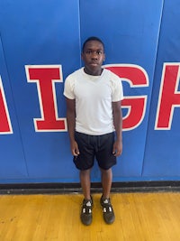 a young man standing in front of a high school wall