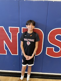 a young boy standing in front of a basketball wall