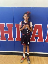 a girl in a basketball uniform standing in front of a wall