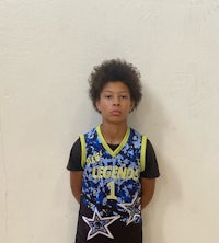 a young boy in a basketball uniform standing in front of a wall