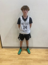 a young boy in a basketball uniform standing in front of a wall