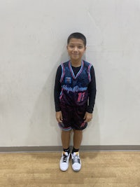 a young boy in a basketball uniform posing for a photo