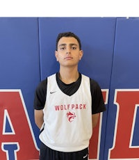 a young man standing in front of a wall with a wolfpack logo