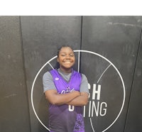 a young girl in a purple uniform standing in front of a wall