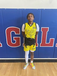 a young man in a yellow and black uniform standing in front of a basketball court