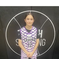 a girl in a purple and white basketball uniform standing in front of a wall