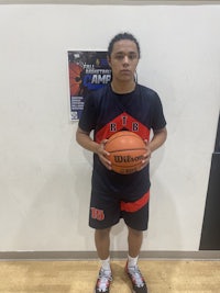 a young man holding a basketball in front of a wall