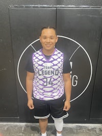 a young boy wearing a purple and white basketball jersey