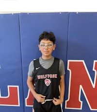 a young boy in a basketball uniform standing in front of a wall