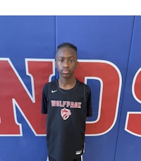 a young boy in a basketball uniform standing in front of a wall