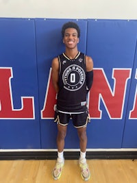 a young man in a basketball uniform standing in front of a wall