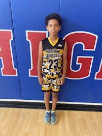 a young boy in a basketball uniform standing in front of a wall