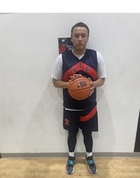 a man holding a basketball in front of a wall