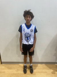 a young boy in a basketball uniform standing in front of a wall