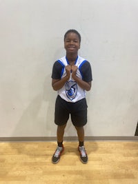 a young boy in a basketball uniform posing for a picture