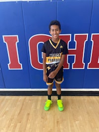 a young boy standing in front of a basketball court