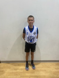 a young boy in a basketball uniform standing in front of a wall