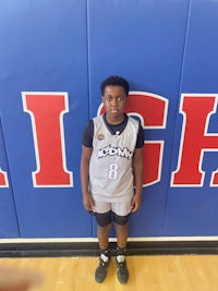 a young boy in a basketball uniform standing in front of a wall