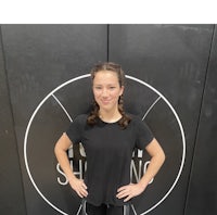 a young girl standing in front of a black wall