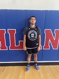a young man standing in front of a basketball court