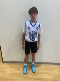 a young boy in a basketball uniform standing in front of a wall