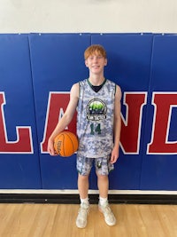 a young man holding a basketball in front of a wall