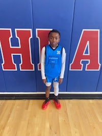 a young boy standing in front of a basketball court