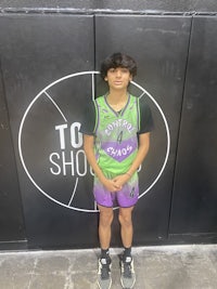 a young man posing in front of a basketball court