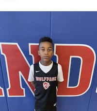 a young boy in a basketball uniform standing in front of a wall