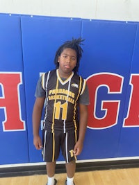 a young man in a basketball uniform standing in front of a wall