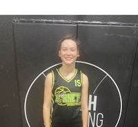 a girl in a basketball uniform standing in front of a wall