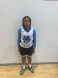 a girl in a basketball uniform standing in front of a wall