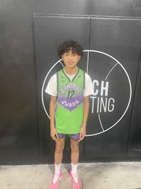 a young boy in a basketball uniform standing in front of a wall