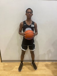 a young man holding a basketball in front of a wall