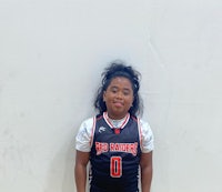 a young girl in a basketball uniform posing for a picture