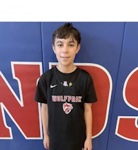 a boy in a black t - shirt standing in front of a wall