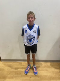 a young boy in a basketball uniform standing in front of a wall