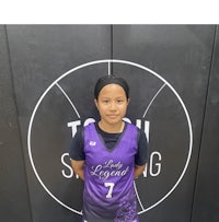 a young girl in a purple basketball uniform standing in front of a wall