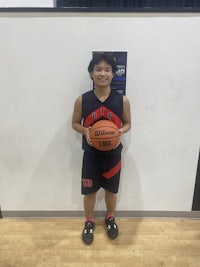 a boy holding a basketball in front of a wall