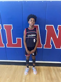 a young boy in a basketball uniform standing in front of a wall