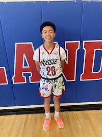 a young boy standing in front of a basketball court