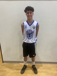 a young man in a basketball uniform standing in front of a wall