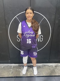 a girl in a purple uniform standing in front of a basketball court