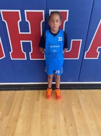 a young girl standing in front of a basketball court